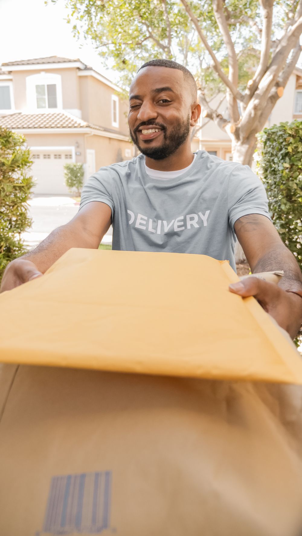 Smiling courier handing parcels to a customer in a residential neighbourhood