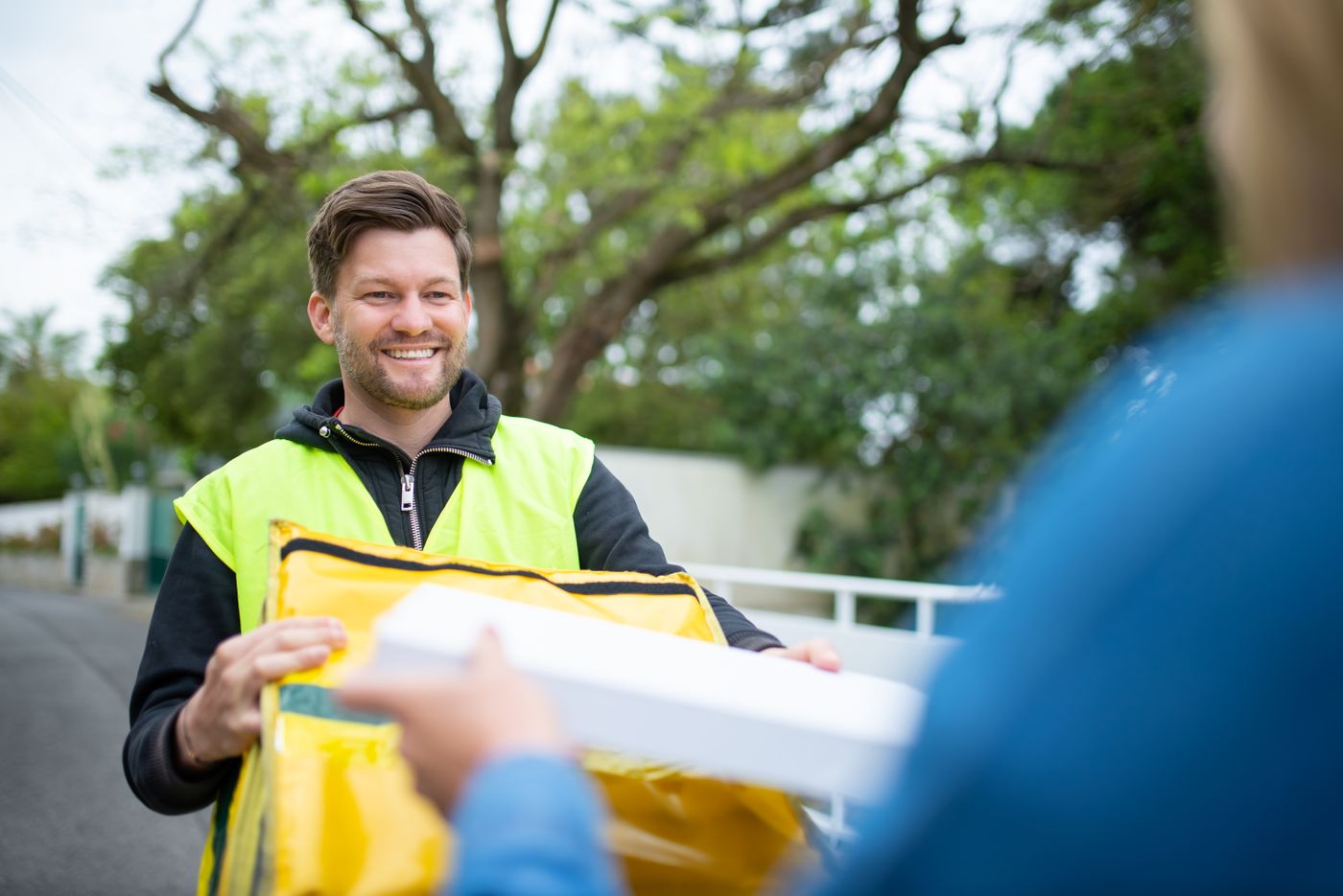 Smiling delivery driver handing a parcel to a customer outdoors
